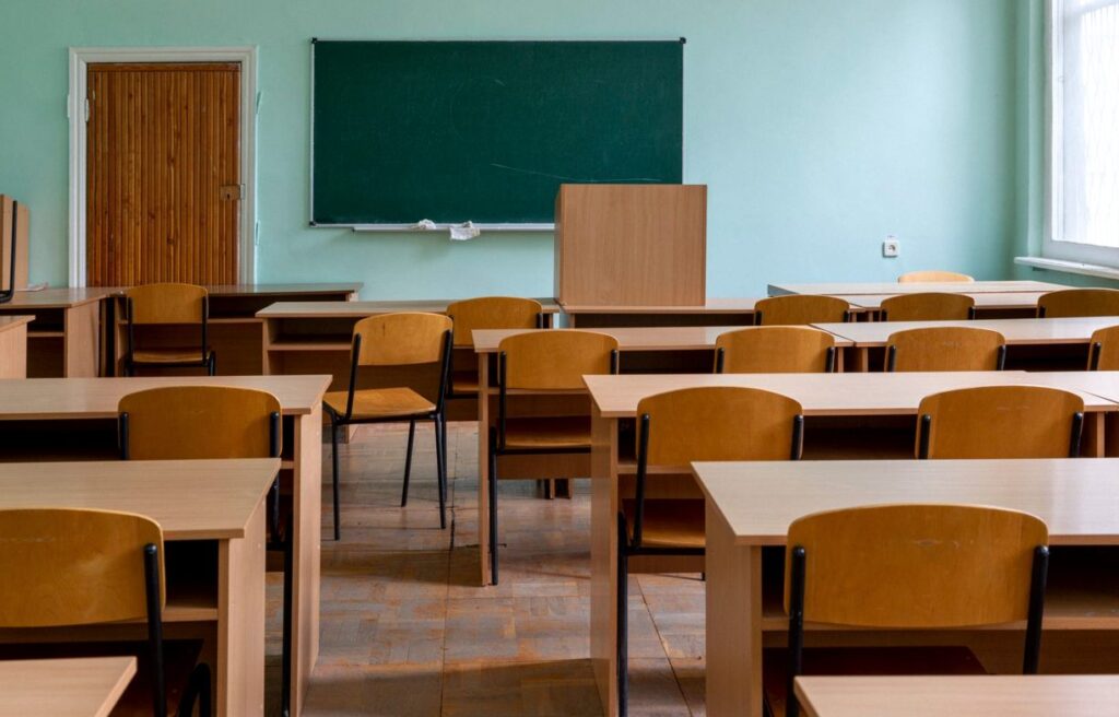 Pusta sala lekcyjna z rzędami ławek i tablicą